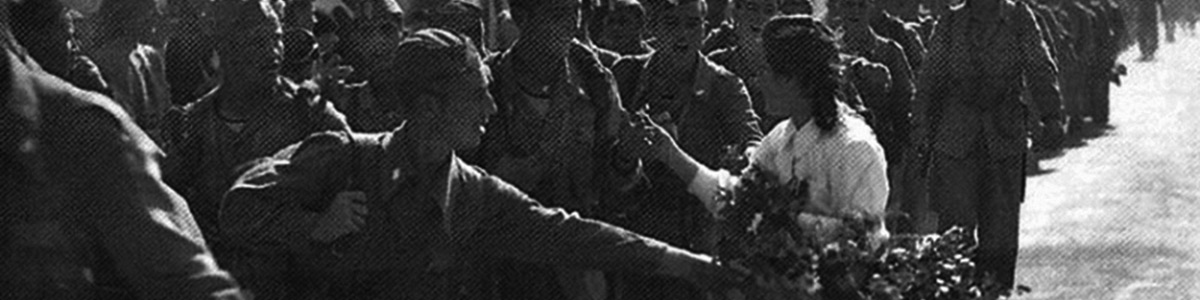 Foto d'epoca in bianco e nero in cui si vedono i soldati polacchi entrare a Senigallia. Una ragazza offre loro dei fiori, ne ha un cesto sottobraccio e i soldati allungano le braccia per averne uno