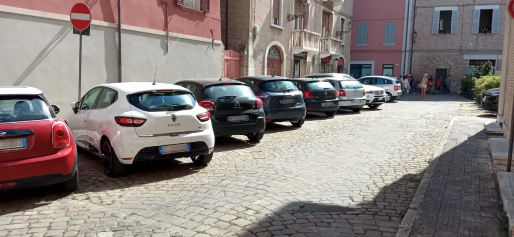 10 auto parcheggiate in pieno centro storico e pedoni che camminano sull sfondo